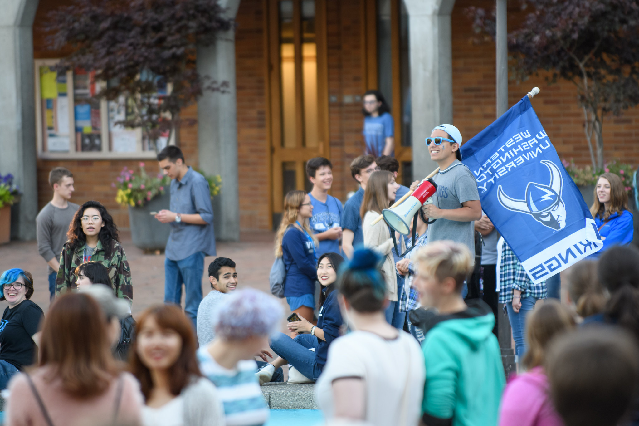 A student holding a megaphone and a WWU Athletics flag with a Viking logo